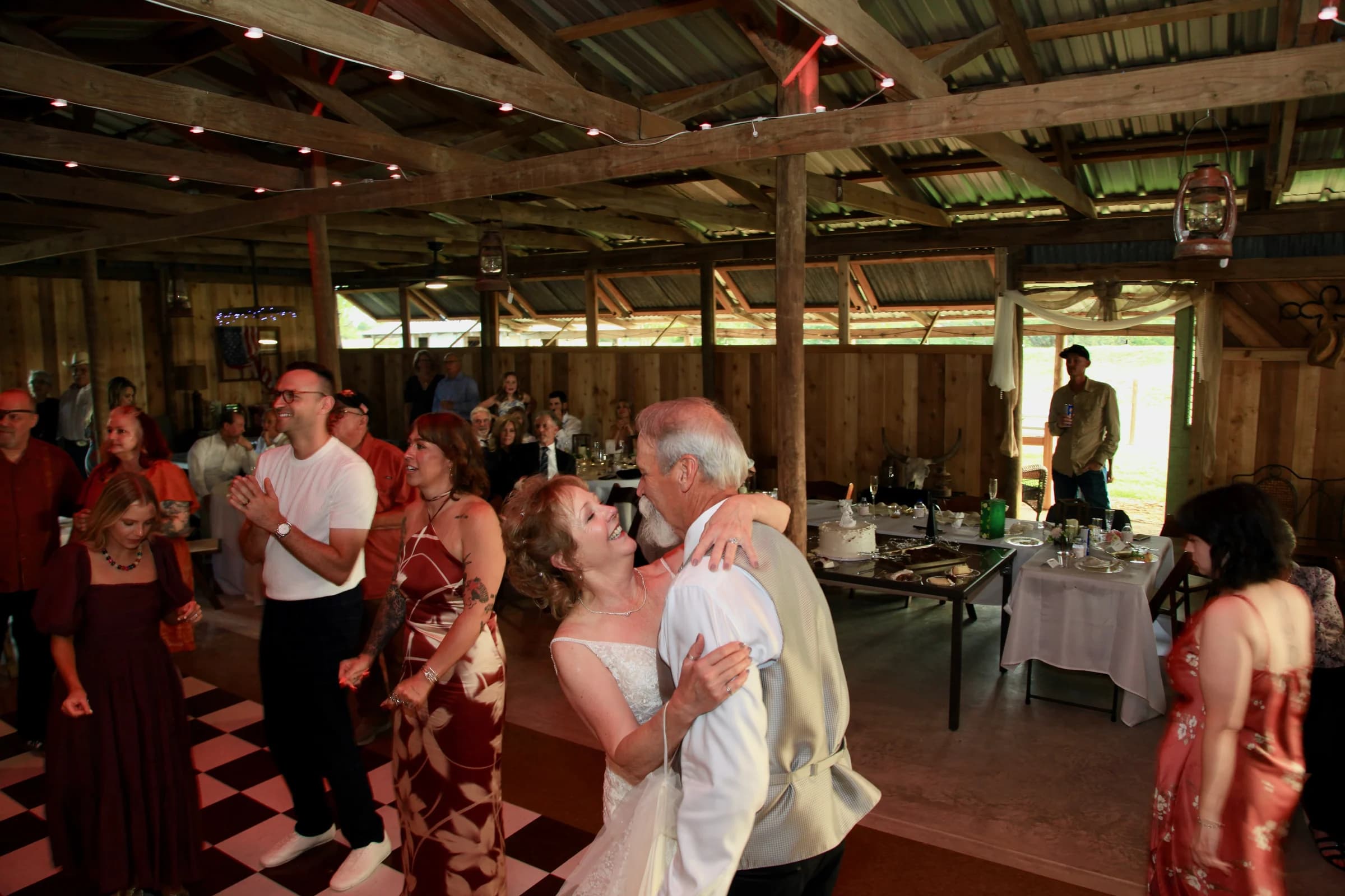 Wedding guests dancing together on the barn’s checkered dance floor