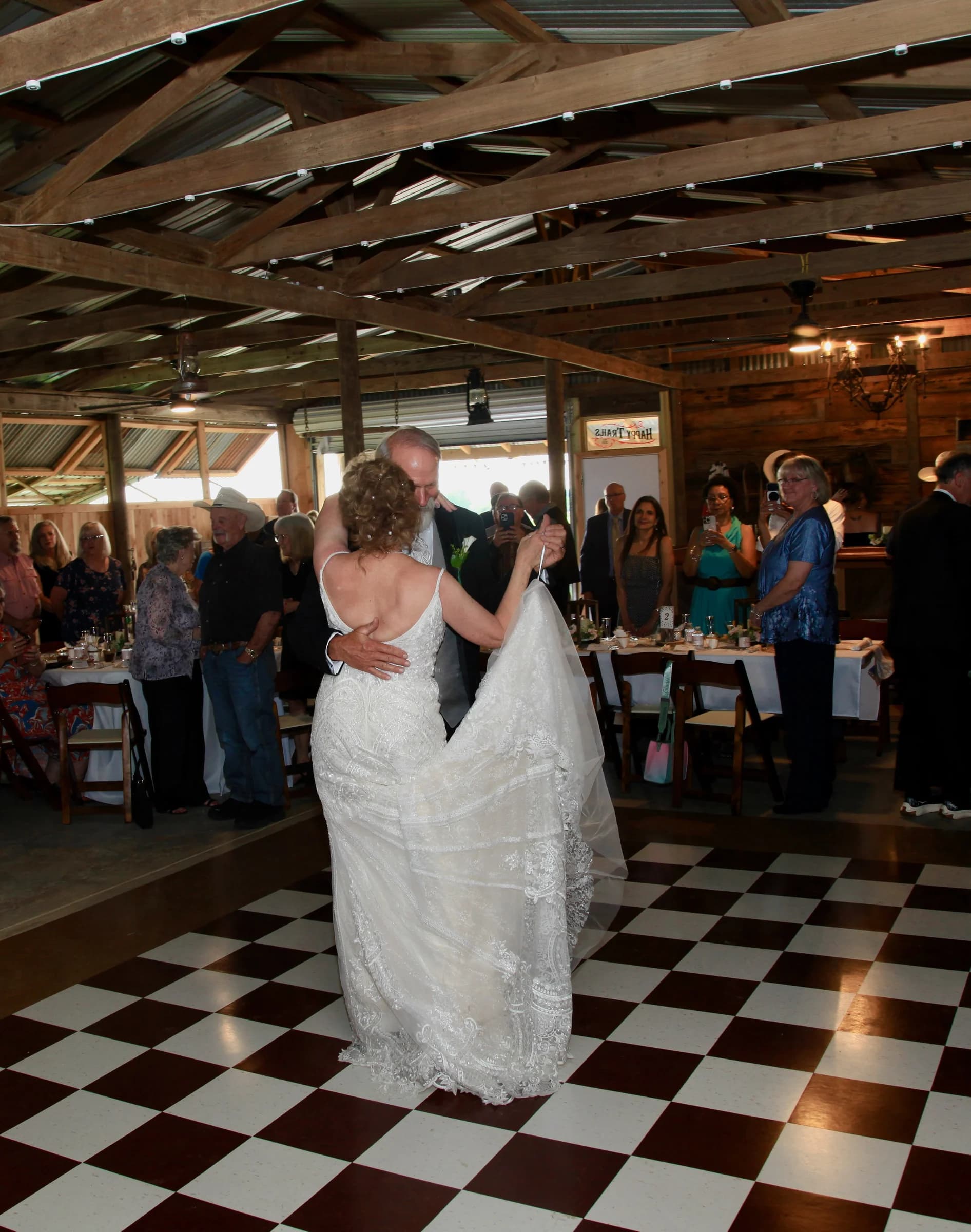 A bride and groom sharing a dance beneath the barn’s wooden rafters